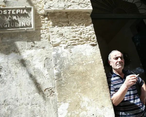 Uomo fuma davanti alla trattoria Angiolino a Lecce.
