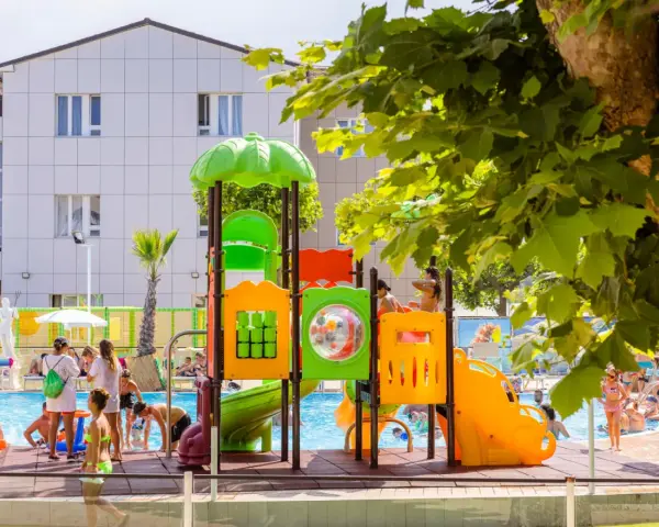 Bambini giocano in piscina e su uno scivolo colorato, un'immagine che riflette le positive recensioni di Color Perla Village.