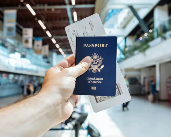 Passaporto USA e boarding pass pronti per il viaggio. L'aeroporto fa da sfondo.