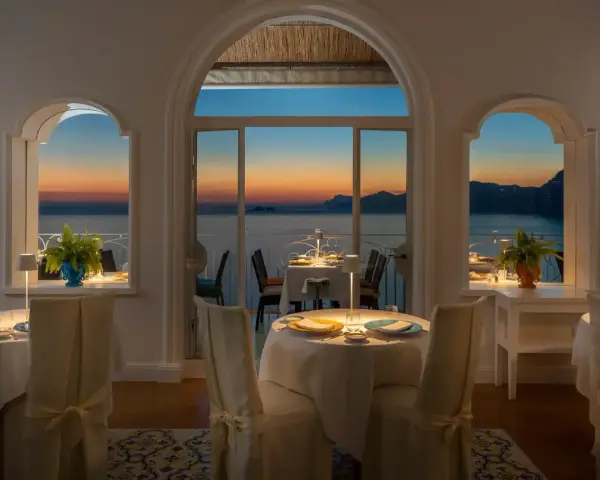 Tavoli apparecchiati nel ristorante dell'hotel Tramonto d'Oro, con vista sul mare al tramonto.