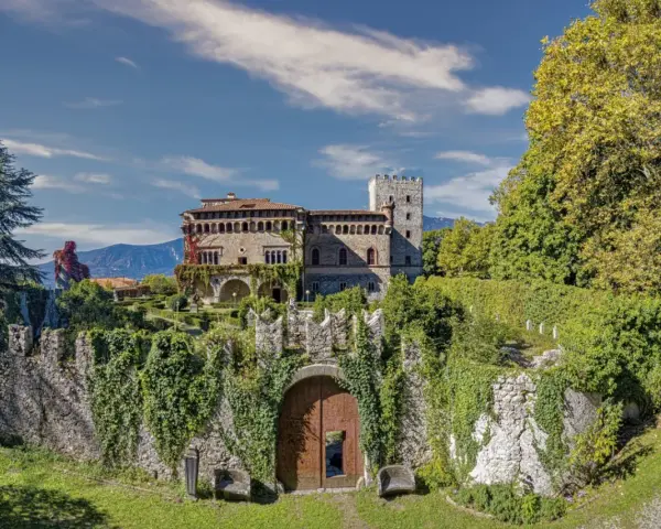 Villa d'Ayala, un castello incantevole con torri e giardini lussureggianti, immerso tra le montagne sotto un cielo azzurro.