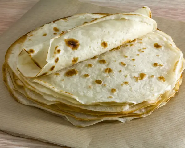 Impasto piadina appena cotto, impilato su carta da forno. Le sottili sfoglie dorate invitano a essere farcite.