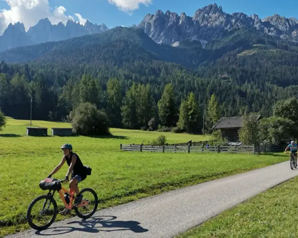 Ciclisti lungo la ciclabile San Candido Lienz, tra prati verdi e montagne maestose. Un'avventura di chilometri immersi nella natura.