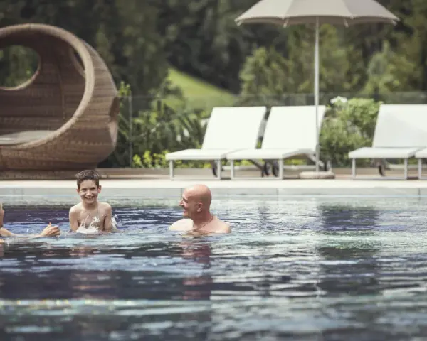 Famiglia felice si diverte in piscina al Cavallino Bianco Family Spa Grand Hotel. Relax e gioia per tutti.