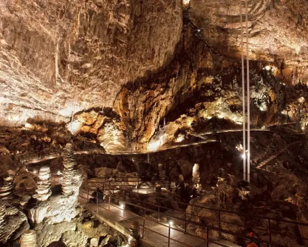 Sentiero illuminato tra stalattiti e stalagmiti in una delle magnifiche grotte in Italia. Un viaggio sotterraneo mozzafiato.