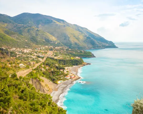 Panoramica di una costa montuosa con un villaggio affacciato sul mare turchese. Perfetto per itinerari Basilicata in macchina.