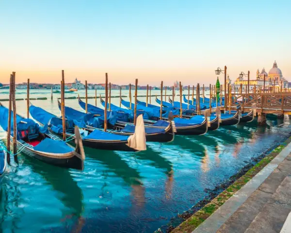 Gondole blu ormeggiate a Venezia, un modo suggestivo per muoversi spendendo poco.