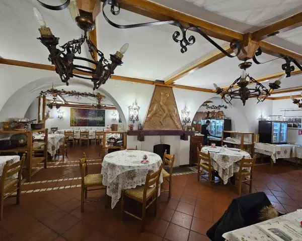 Interno di un ristorante con tavoli apparecchiati e un camino decorato. Un'ottima opzione per sapere dove mangiare a Potenza.