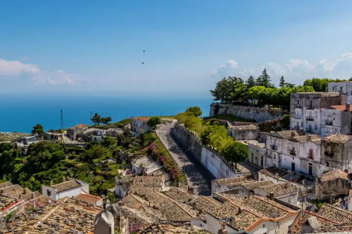 Panoramica di un borgo collinare con vista mare. Per raggiungere l'università Monte Sant'Angelo Napoli, si percorre una strada tortuosa tra case antiche.
