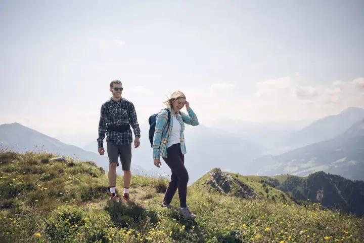 Coppia escursionista sorridente in montagna. L'aria di montagna fa bene al raffreddore, rigenera corpo e mente.