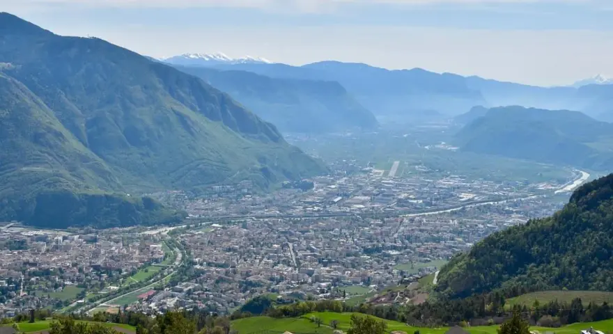 Vista panoramica di Bolzano e della valle, con montagne verdi e innevate sullo sfondo. Perfetto per scoprire cosa fare a Bolzano in un giorno.