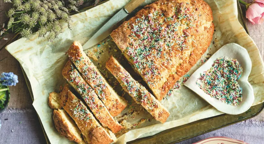 Dolce tipico romagnolo, un ciambellone soffice decorato con zuccherini colorati, pronto per essere gustato.