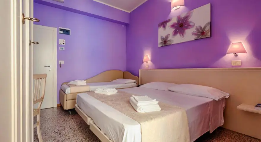 Camera accogliente con letti comodi e pareti viola, ideale per un soggiorno rilassante al Hotel Plaza Gabicce Mare.