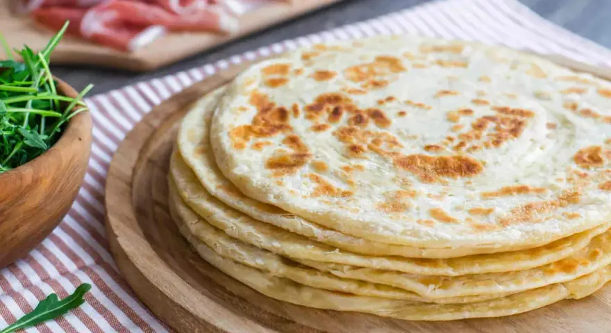 Pila di piadine marchigiane, pronte per essere farcite con rucola e salumi.