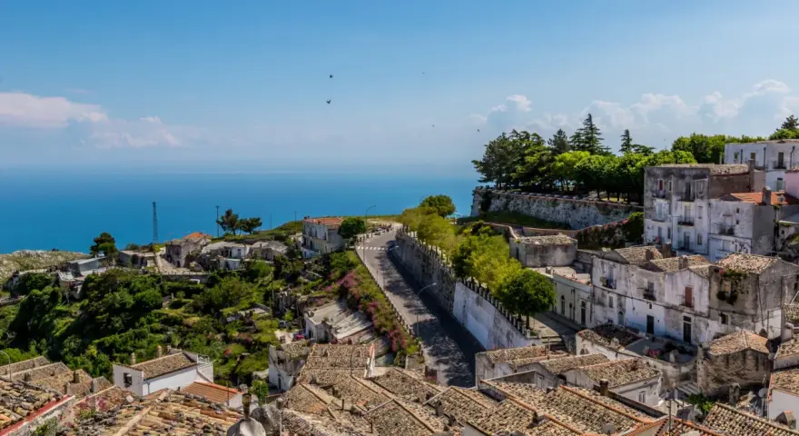 Panoramica di un borgo collinare con vista mare. Per raggiungere l'università Monte Sant'Angelo Napoli, si percorre una strada tortuosa tra case antiche.