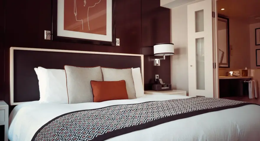 Letto in una camera doppia, con copriletto geometrico e quadro astratto. Il significato di camera doppia è un luogo accogliente.