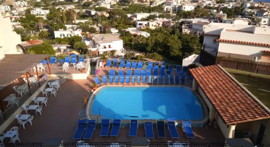 Piscina e lettini prendisole al **hotel tramonto Ischia**, con vista sul mare e sul paese.