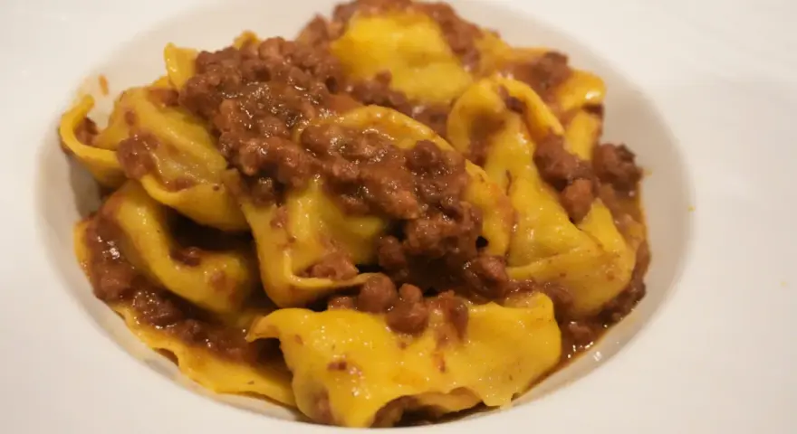 Tortellini fatti in casa con ragù, un classico dei primi piatti romagnoli.