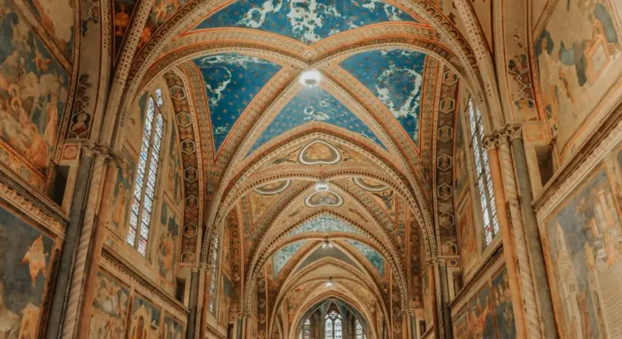 Volte affrescate con cielo stellato e scene sacre nella Basilica Superiore di San Francesco, cuore del centro storico di Assisi.