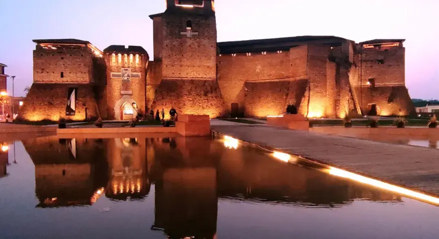 Castello illuminato di sera, riflesso sull'acqua. Un luogo magico che evoca il mondo di Fellini.