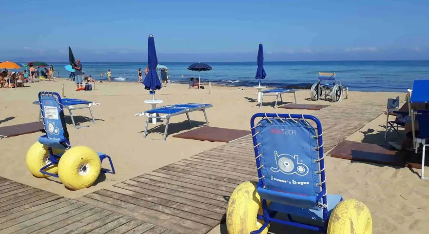 Carrozzine speciali e passerelle per vacanze per disabili con assistenza su una spiaggia attrezzata.