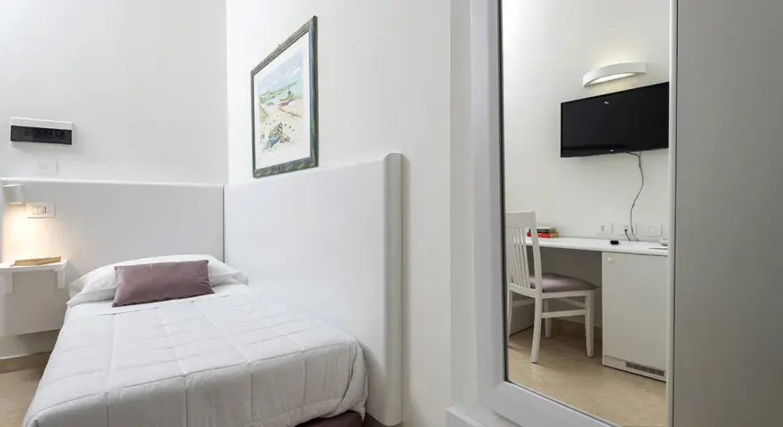 Accogliente camera singola hotel con letto, scrivania e TV visibili nello specchio.