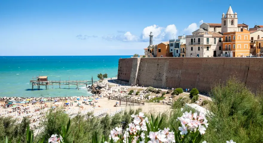 Vista di una spiaggia affollata con un trabucco sul mare e il borgo antico di Termoli. Perfetto per scoprire cosa vedere vicino a Termoli.