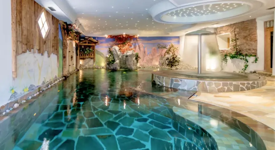 Piscina interna con cascata e decorazioni naturali, un'oasi di relax all'Hotel Sporting Andalo.
