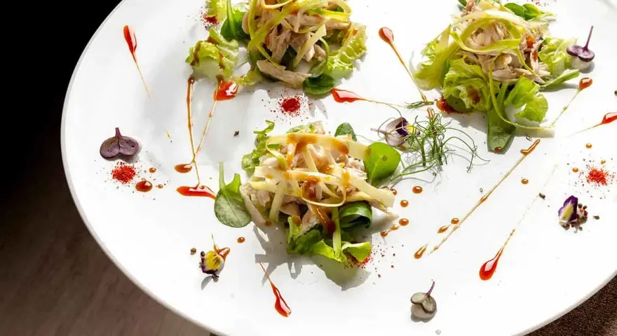 Tre porzioni di insalata di pollo e verdure su un piatto bianco, un'ottima opzione per trattorie economiche a Bra.