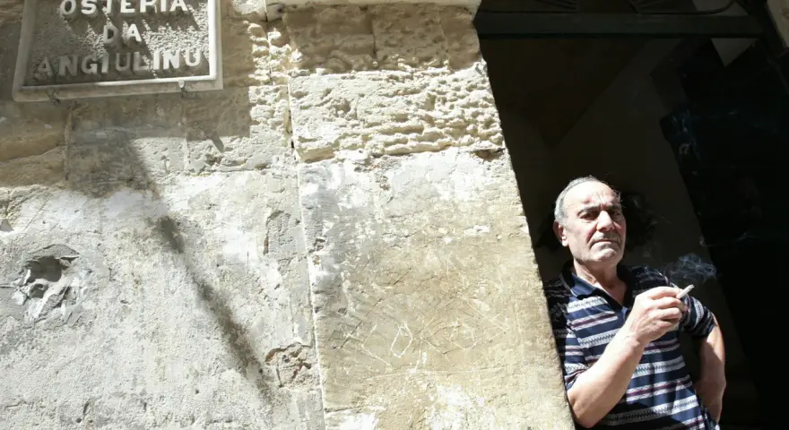 Uomo fuma davanti alla trattoria Angiolino a Lecce.