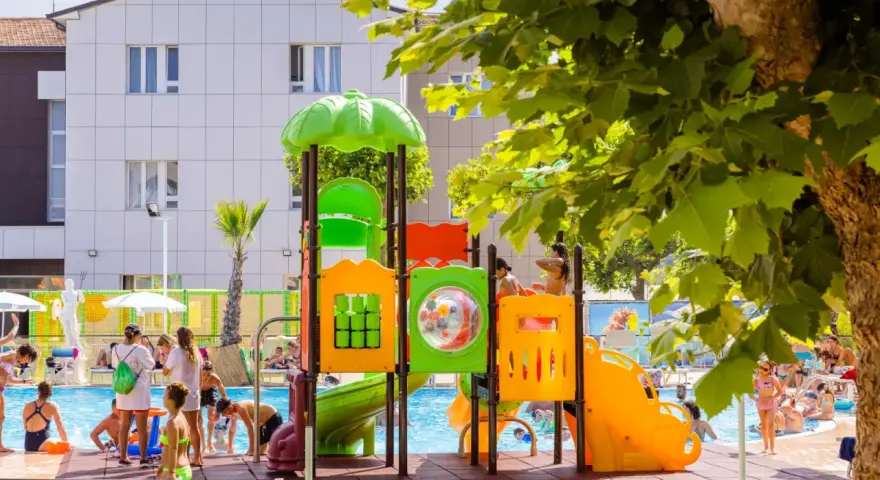 Bambini giocano in piscina e su uno scivolo colorato, un'immagine che riflette le positive recensioni di Color Perla Village.