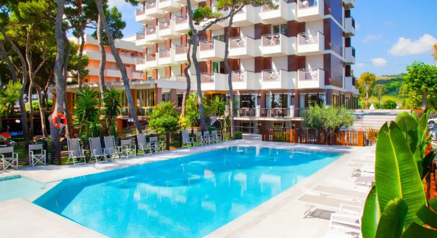Piscina azzurra e lettini prendisole davanti al **promenade hotel giulianova**, circondati da pini e vegetazione lussureggiante.