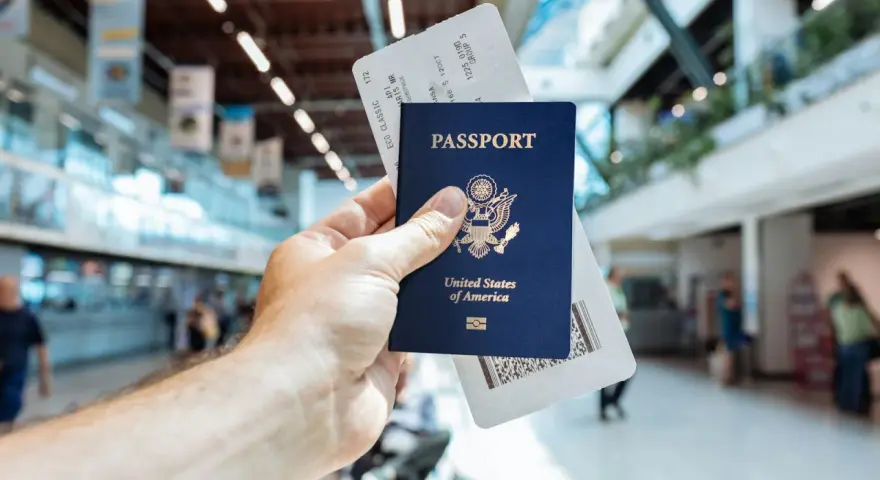 Passaporto USA e boarding pass pronti per il viaggio. L'aeroporto fa da sfondo.