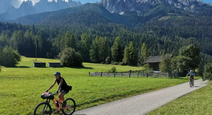 Ciclisti lungo la ciclabile San Candido Lienz, tra prati verdi e montagne maestose. Un'avventura di chilometri immersi nella natura.