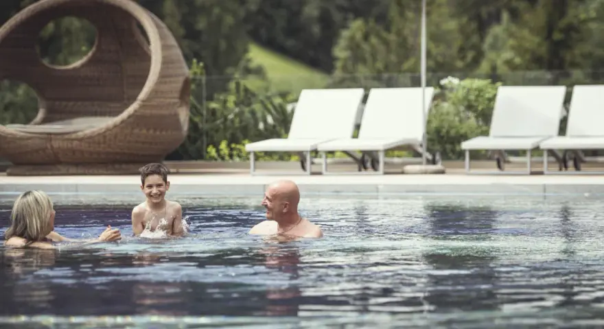 Famiglia felice si diverte in piscina al Cavallino Bianco Family Spa Grand Hotel. Relax e gioia per tutti.