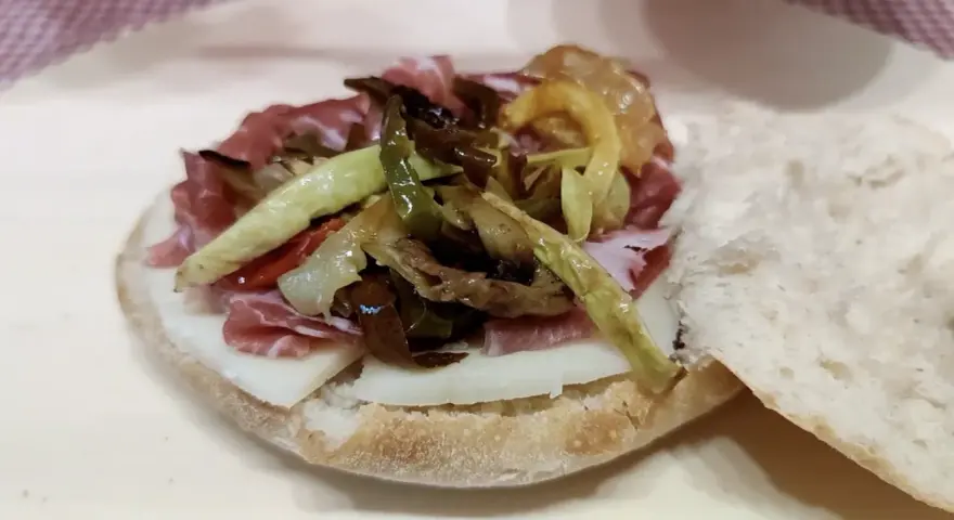 Puccia leccese con salumi, formaggio e verdure grigliate, un sapore autentico del Salento.