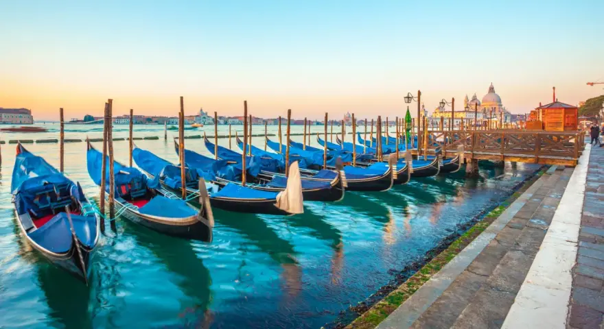 Gondole blu ormeggiate a Venezia, un modo suggestivo per muoversi spendendo poco.
