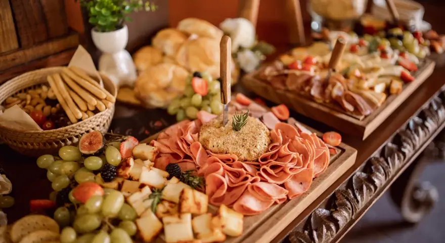 Un ricco buffet con salumi, formaggi, frutta e pane, un vero banchetto che fa pensare alla pensione completa significato: tutto incluso per godersi il momento.