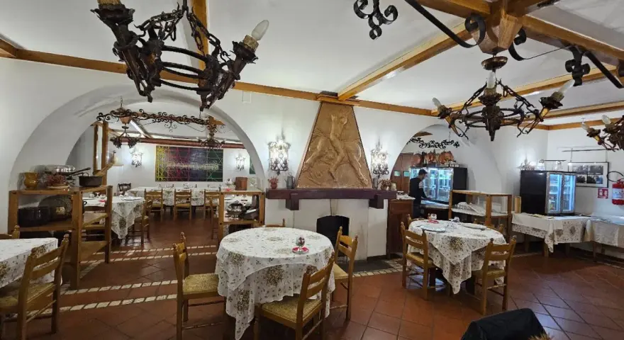 Interno di un ristorante con tavoli apparecchiati e un camino decorato. Un'ottima opzione per sapere dove mangiare a Potenza.