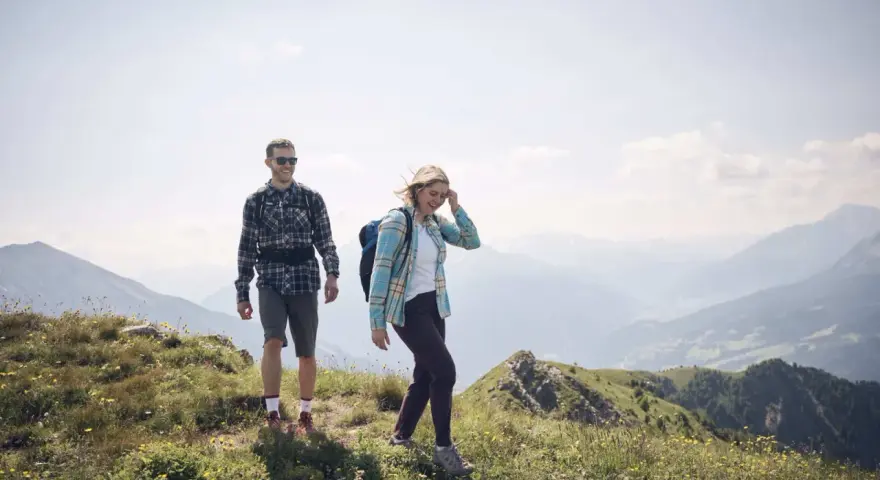 Coppia escursionista sorridente in montagna. L'aria di montagna fa bene al raffreddore, rigenera corpo e mente.