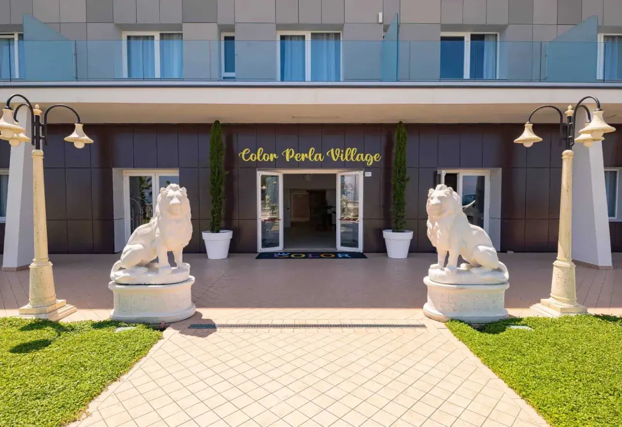 Ingresso del Color Perla Village con leoni di pietra, cipressi e lampioni. Le recensioni di Color Perla Village lodano l'accoglienza.
