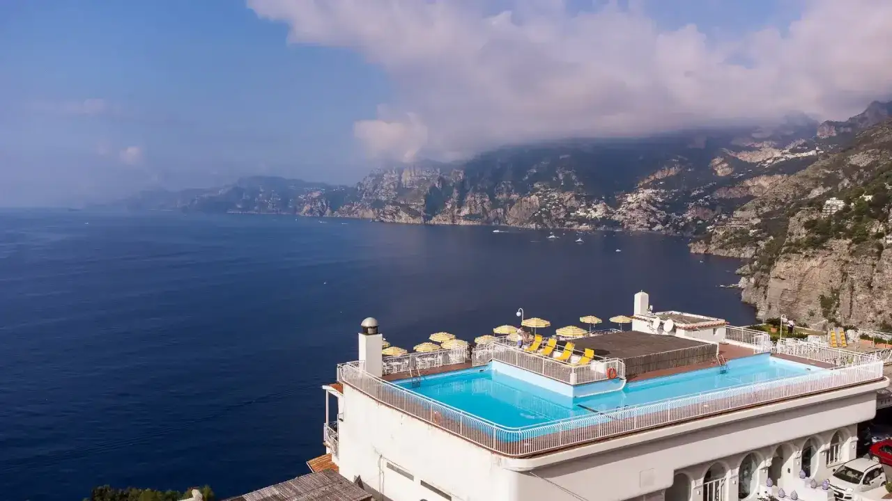 Piscina panoramica con vista mare mozzafiato, lettini e ombrelloni gialli. Il hotel tramonto d'oro offre un sogno di vacanza sulla costa.