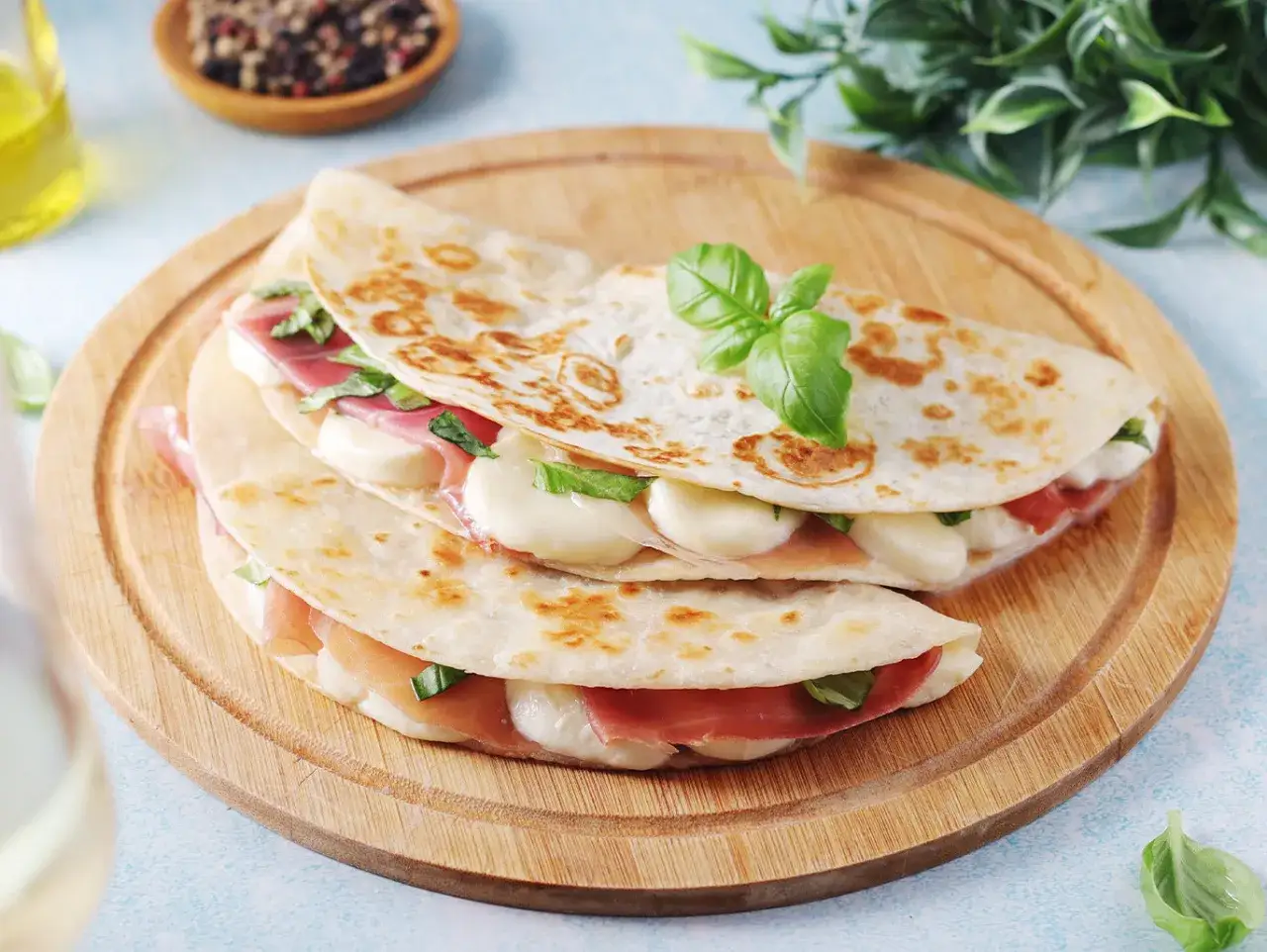 Piadine con strutto, prosciutto e mozzarella filante, guarnite con basilico fresco. Una deliziosa ricetta per un pasto veloce e gustoso.