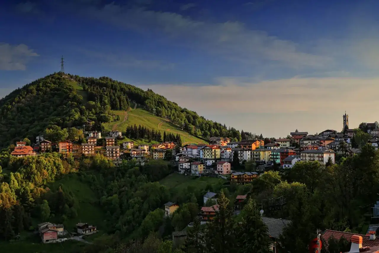Panoramica di Selvino, un borgo tra i boschi con case colorate e un campanile. Perfetto per scoprire cosa fare a Selvino.