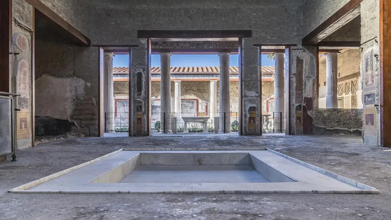 Interno di una domus pompeiana con vasca centrale e resti di censurati affreschi pompei sulle pareti.