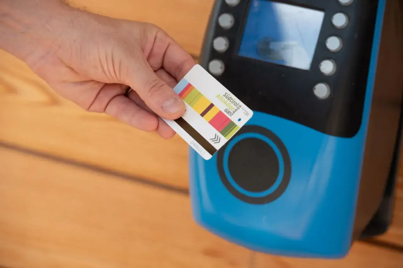 Mano che avvicina una mobility card Alto Adige a un lettore blu.