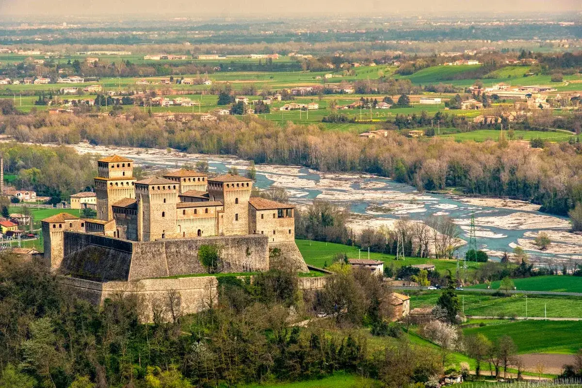 Imponente fortezza medievale, uno dei castelli vicino Parma, domina un paesaggio collinare con un fiume serpeggiante.