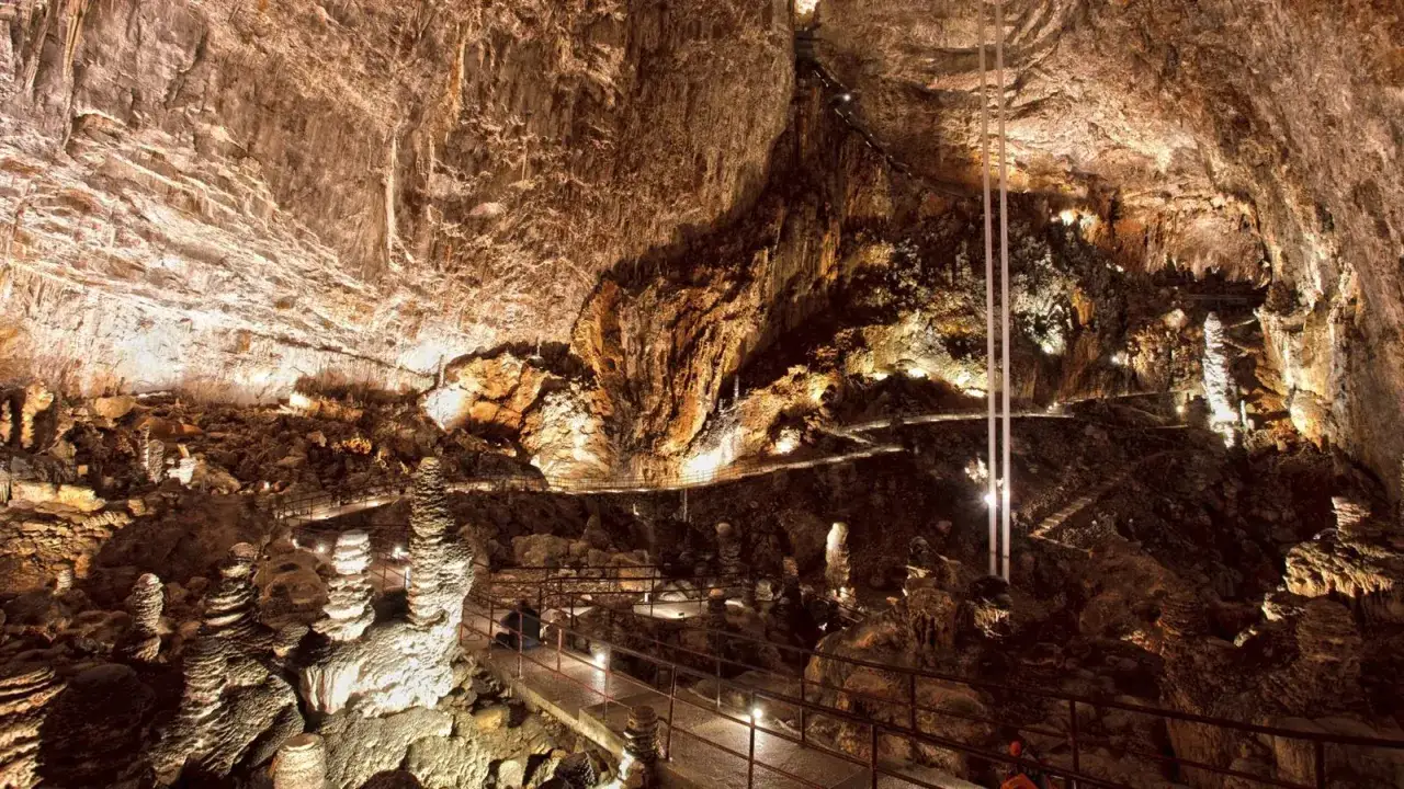 Sentiero illuminato tra stalattiti e stalagmiti in una delle magnifiche grotte in Italia.