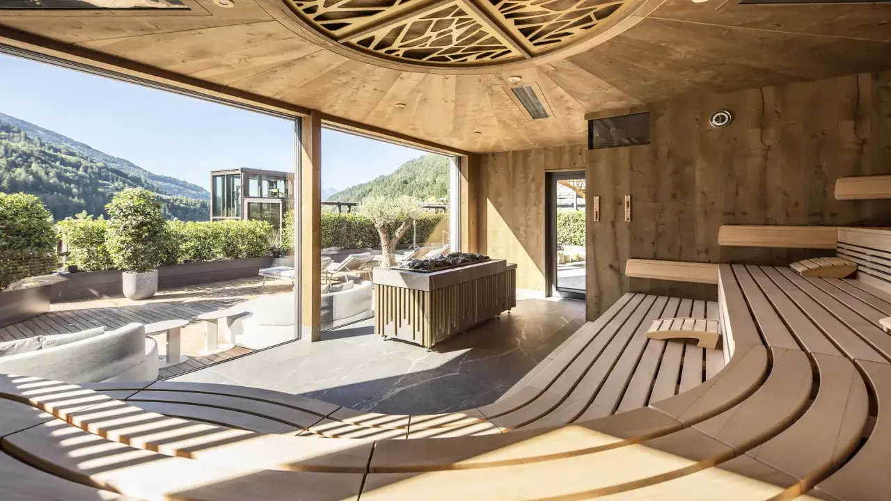 Interno moderno e lussuoso della sauna dell'hotel Quellenhof Merano, con vista panoramica sulle montagne.