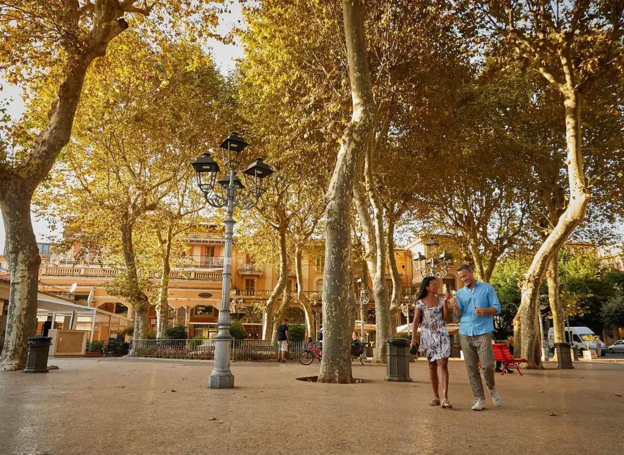 Coppia passeggia nel centro storico di Fiuggi, tra alberi dalle foglie dorate e palazzi d'epoca.